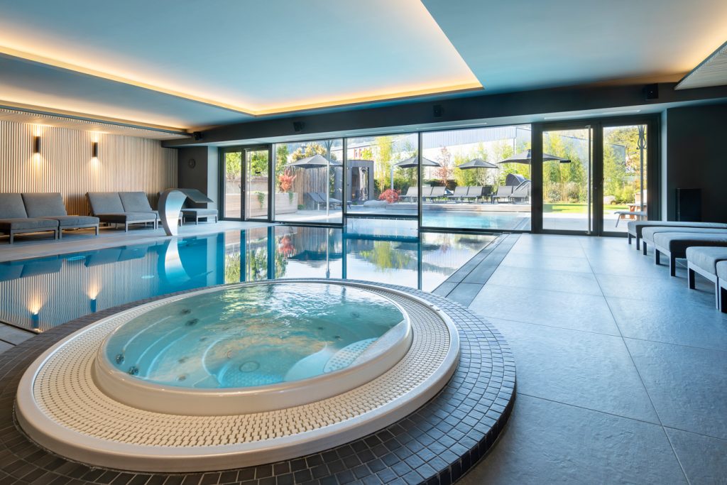 Piscine et jacuzzi intérieurs du spa , devant des baies vitrées donnant sur la terrasse de l'hôtel