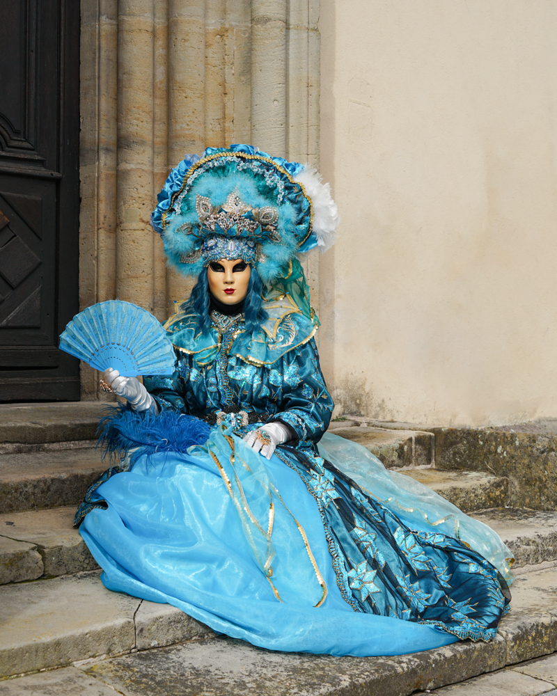 Een vrouw in een blauwe jurk tijdens het Venetiaanse carnaval van 2025 in Remiremont.